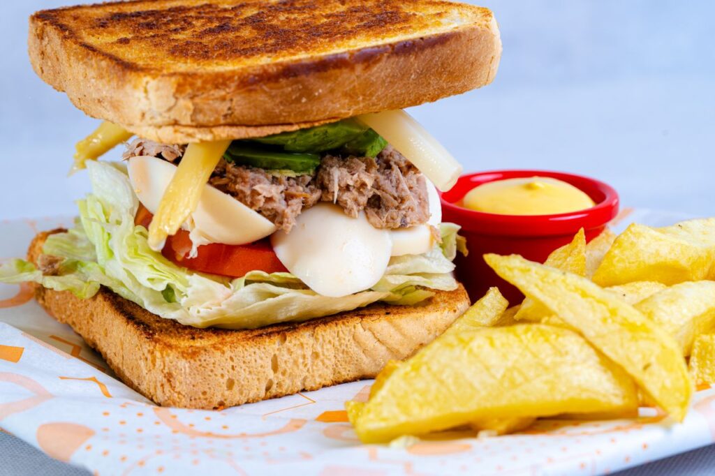 Delicious sandwich with lettuce, cheese, and fries on a colorful table setting.